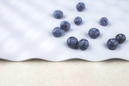 blue blueberries are scattered in a chaotic order on a gray background with space for text, close-up, blur.の写真素材