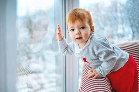 the kid carefully looks out the window at the snow and what is happening around, side view, close-up...