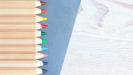 colored pencils are laid out on a gray and wooden backgroundの写真素材