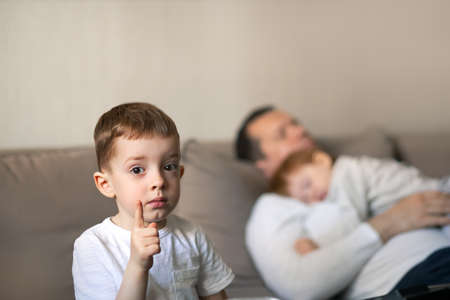 Toddler and dad sleeping on the couch during the day, concept childrens day and Parental care. Focus on the hands.の写真素材