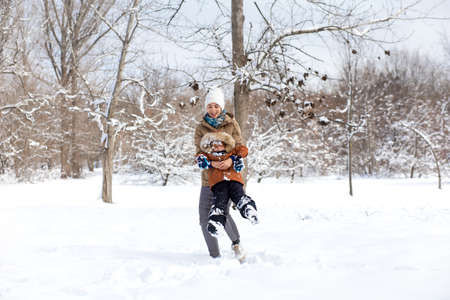 Mom plays with her child outdoors in winter.の写真素材