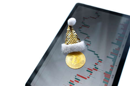 bitcoin cryptocurrency coin in the hat of Santa lies on the tablet with the display of the cryptocurrency chart.の写真素材