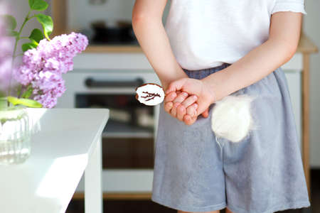 a boy in a rabbit costume hides a bitten Easter cookie behind his backの写真素材