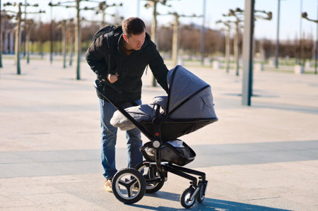 A young dad with a baby stroller on an outdoor walk in the fall.の写真素材