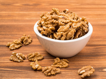 white cups with walnut, bowls with handful of nuts  on a wooden backgroundの写真素材