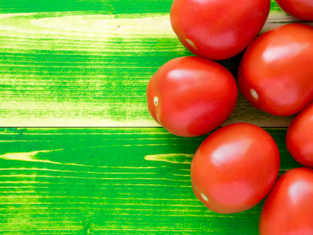 ripe red tomatoes on bright green wooden background table, top viewの写真素材