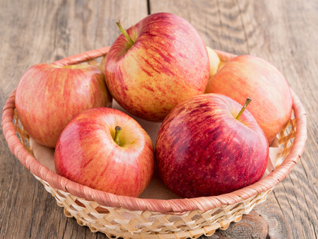 ripe juicy red apples in a basket on a wooden tableの写真素材