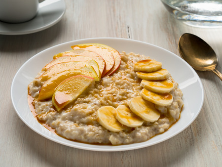 Healthy Breakfast in the morning - oatmeal with fruit and honey, slices of apples and bananas, caramel syrup.  Selective focusの写真素材