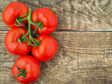 branch of ripe tomatoes on rustic weathered wooden table, top view, empty space for text.の写真素材