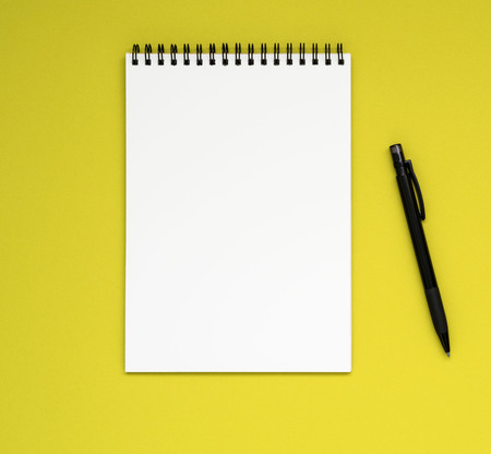 open notepad on the spiral with a clean white page and pencil on a bright yellow background colorの写真素材