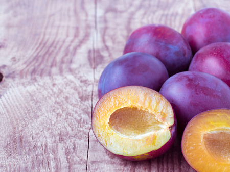 Large red sweet plum and cut off half on a wooden background with empty spaceの写真素材