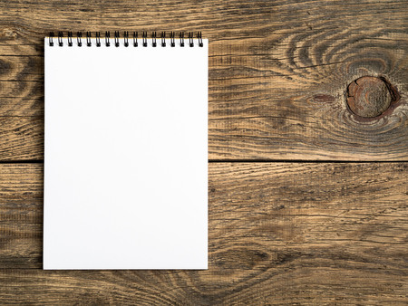 open notepad with a clean white page on wooden table, top viewの写真素材