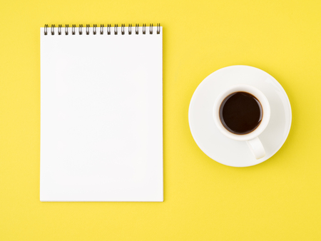 Notepad open with white blank page for writing idea or to-do list, a Cup of coffee  on bright yellow tableの写真素材