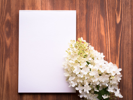 Billboard with blank sheet for notes and white flower hydrangeain abstract blank wooden background....