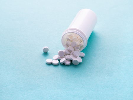 white open container with a medicament and pills on blue backgroundの写真素材