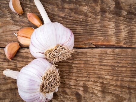 two garlic bulbs and cloves on aged wooden table. Background with blank place for textの写真素材