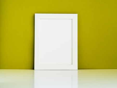 Blank white frame on a white table against the olive colored wall with copy spaceの写真素材