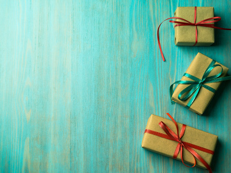 gift packaging, box with shadow with ribbons of red and green on a wooden blue-green table