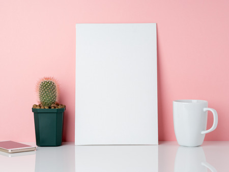 Blank white frame and plant cactus, cup of coffee or tea on a white table against the pink wall with copy space. Mockup with copy space.の写真素材