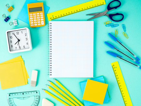 Top view of modern bright blue office desktop with notebook in a cage, school supplies on table, empty space for text. Back to school concept. の写真素材