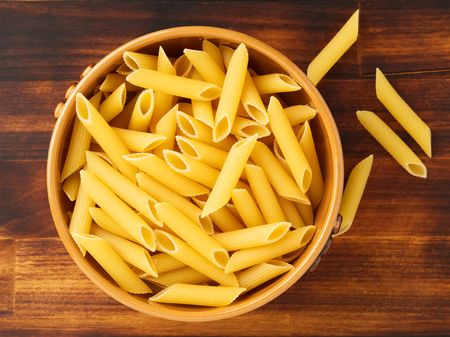 Pasta Tortiglioni in brown bowl on a dark wooden brown table. Top view.の写真素材