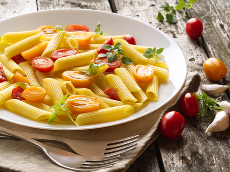 Penne pasta with tomatoes and basil on the old rustic gray wooden background, low-calorie diet, top view, close-upの写真素材