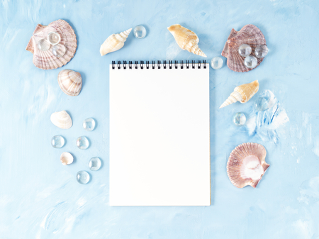 Mock up with frame of seashell and notepad on blue stone background, scallop shell, copy space. Summer concept of holiday by seaの写真素材