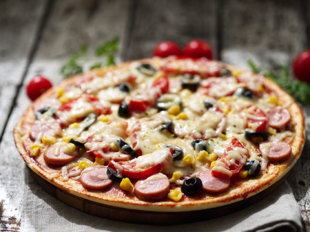 Homemade pizza with parmesan, oregano, olives and mozzarella, sausage and tomato sauce, side view, a day lightの写真素材