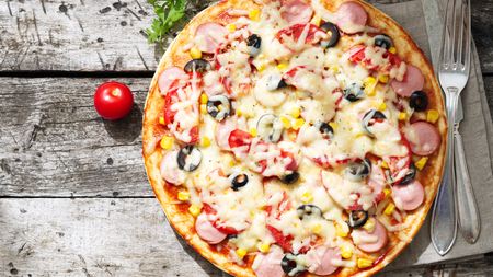 Homemade pizza with parmesan, oregano, olives and a mozzarella, sausage and tomato sauce, top view, copy spaceの写真素材