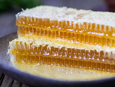 honey in honeycomb on a plate on an old wooden table, close-up, side view