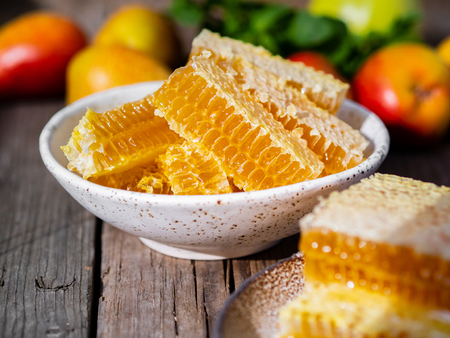 honey in honeycomb, close-up, on white ceramic plate, on wooden rustic table, side view, sunlight in sunny day.の写真素材