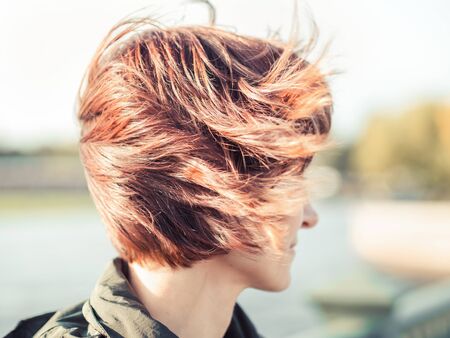 beautiful woman, with brown hair fluttering in wind. Sunny autumn day, street in city center, girl...