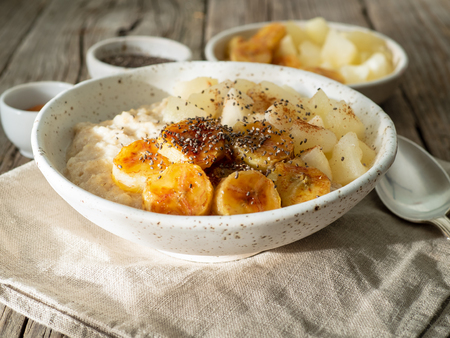 Large bowl of tasty and healthy oatmeal for Breakfast, morning meal. Top view, close up, wooden rustic table, sun light.の写真素材