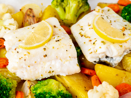 Fish cod baked with vegetables - healthy diet healthy food. Light white marble table, copy space, side view, close up.の写真素材