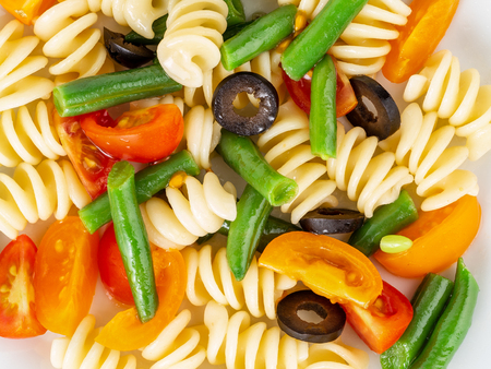 Italian salad with fusilli paste tomatoes, olives, green beans, top view, close up.の写真素材