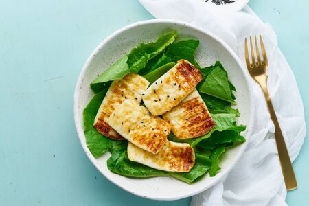 keto ketogenic diet grilled haloumi with lettuce, mediterranean cuisine on blue backgroundの写真素材