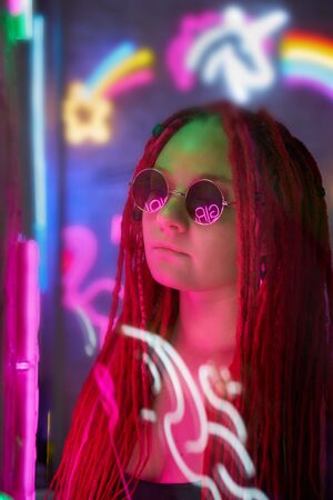Girl in neon lights at party in nightclub, beautiful woman in sunglasses, with long pink hair, with...