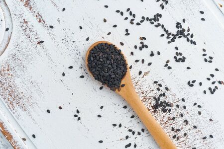Black Sesame on a wooden spoon. White wooden background. Top view, close up. Copy space.の写真素材