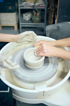 Women making ceramic pottery, concept for a workshop and master class, four hands close-up, focus on potters, palms with pottery. Two woman. Creative hobby concept. Earn extra money, verticalの写真素材