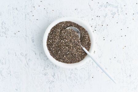 Chia seeds in white bowl on a white stone concrete background, top view, copy spaceの写真素材