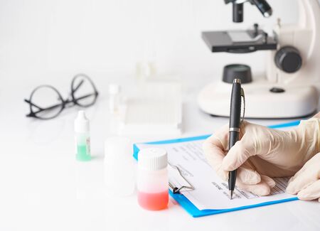 Pandemic COVID-19, Coronavirus. Unrecognizable doctor appoint prescription drugs to patients in hospital on duty, avail for work, filling out forms, conducts tests in laboratory, writes down results.の写真素材