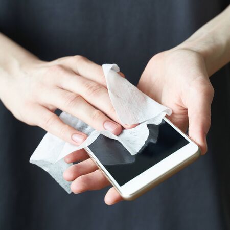 Woman wash cell phone with wet wipes, to prevent illness Novel coronavirus 2019-nCoV after public...