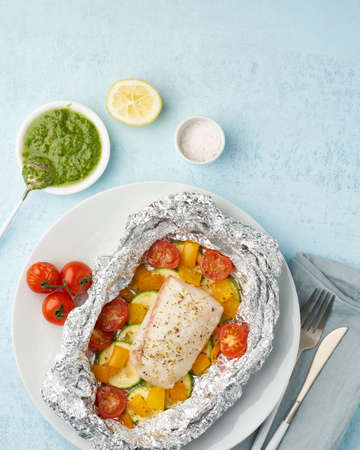 Foil pack dinner with white fish. Oven baked fillet of cod, pike perch with vegetablesの写真素材