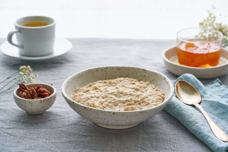 Whole oatmeal, large bowl of porridge with butter for breakfast, morning meal. Side view, close up,...