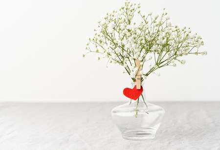 Valentines Day. Delicate white flowers in vase. Red felt heart - symbol of lovers.の写真素材