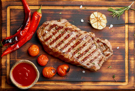 Whole beef steak, fried striploin on wooden cutting board. Keto ketogenic diet.