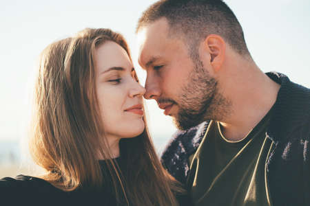 Happy couple in love. Beautiful man and woman look at each other tenderly, close-up portrait. Two together, young family on sunny day. Brunette and brown hair femaleの写真素材