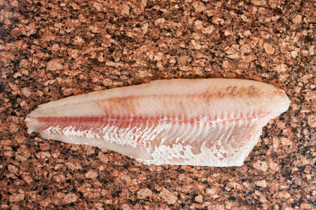 Fresh raw pike perch fish fillet on marble dark brown table. Top view
