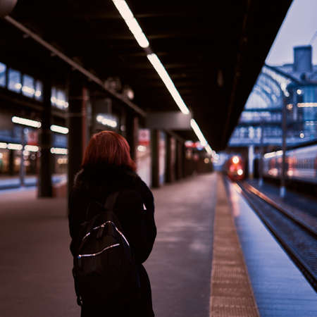 Railway station. Beautiful girl is standing on platform and waiting for train. Woman travels lightの写真素材