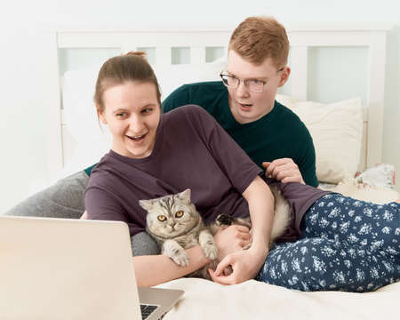 Teen in love lying on bed, watch movies on laptop during quarantine due to coronavirus pandemic